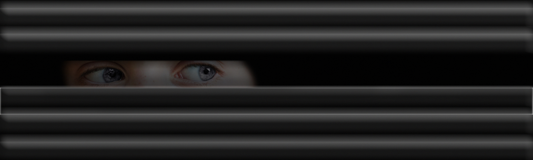 Eyes looking through window blinds