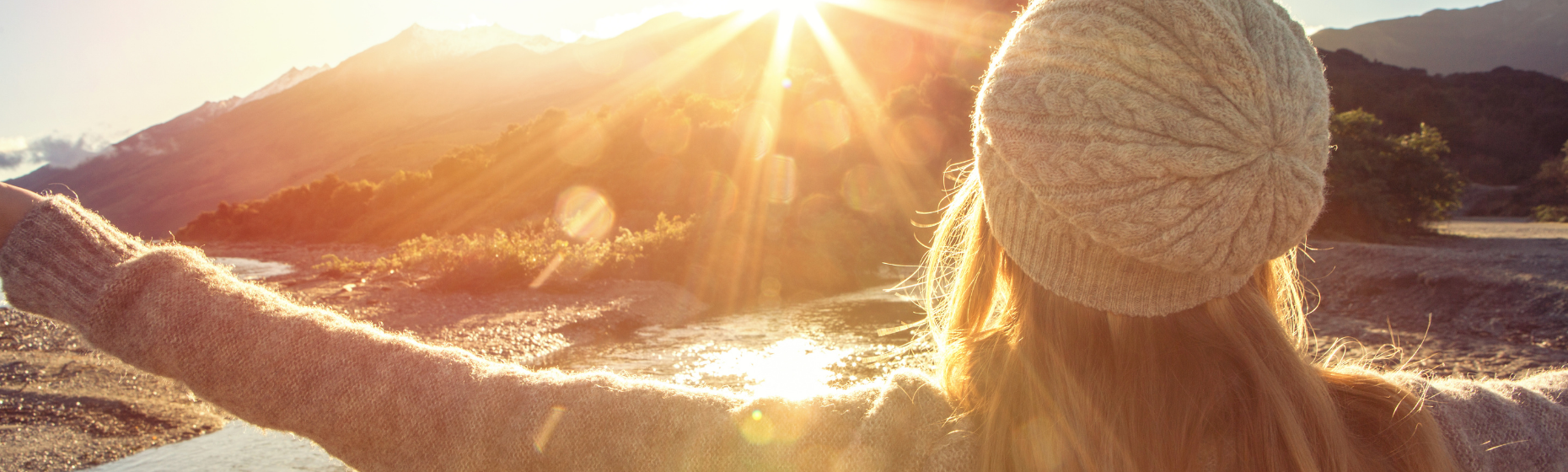 Woman with arms out looking at sunrise